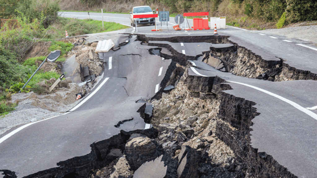 Voiture sur une route de montagne bloquée par des dégâts dus à un séisme.